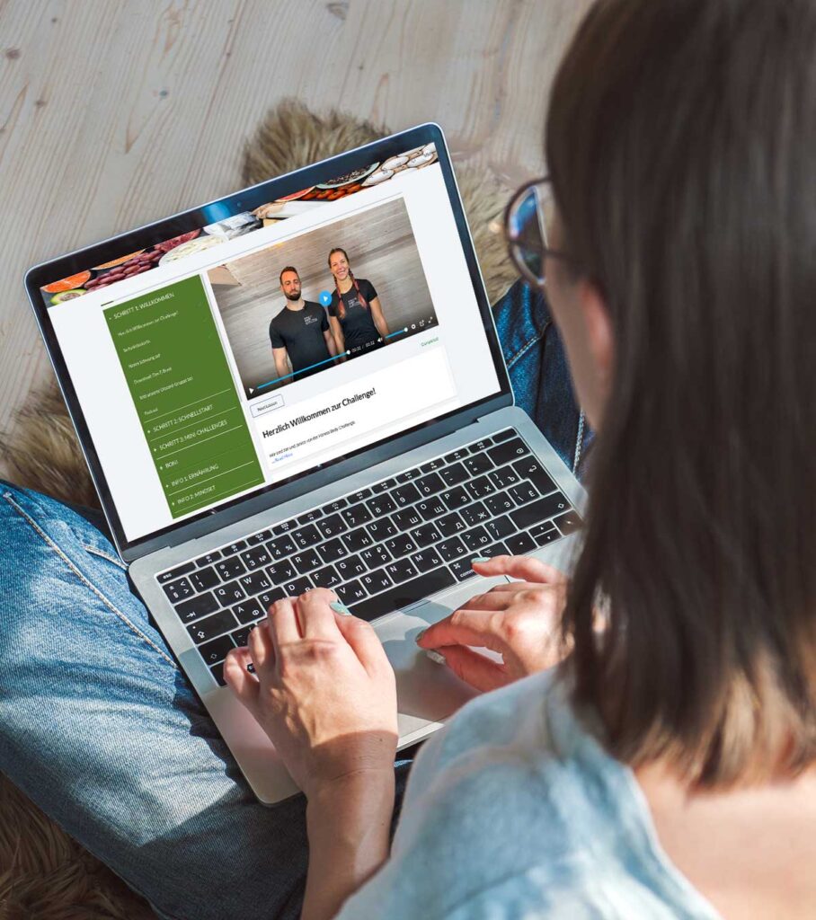 Frau sitzt auf dem Boden und hat einen Laptop auf dem Schoß mit der Webseite von der Fitness Body Challenge